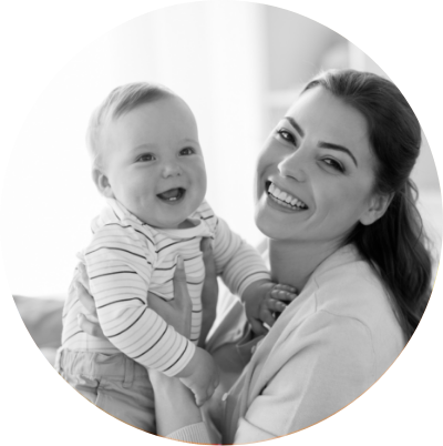 Mother lifting smiling baby in bright room, black and white